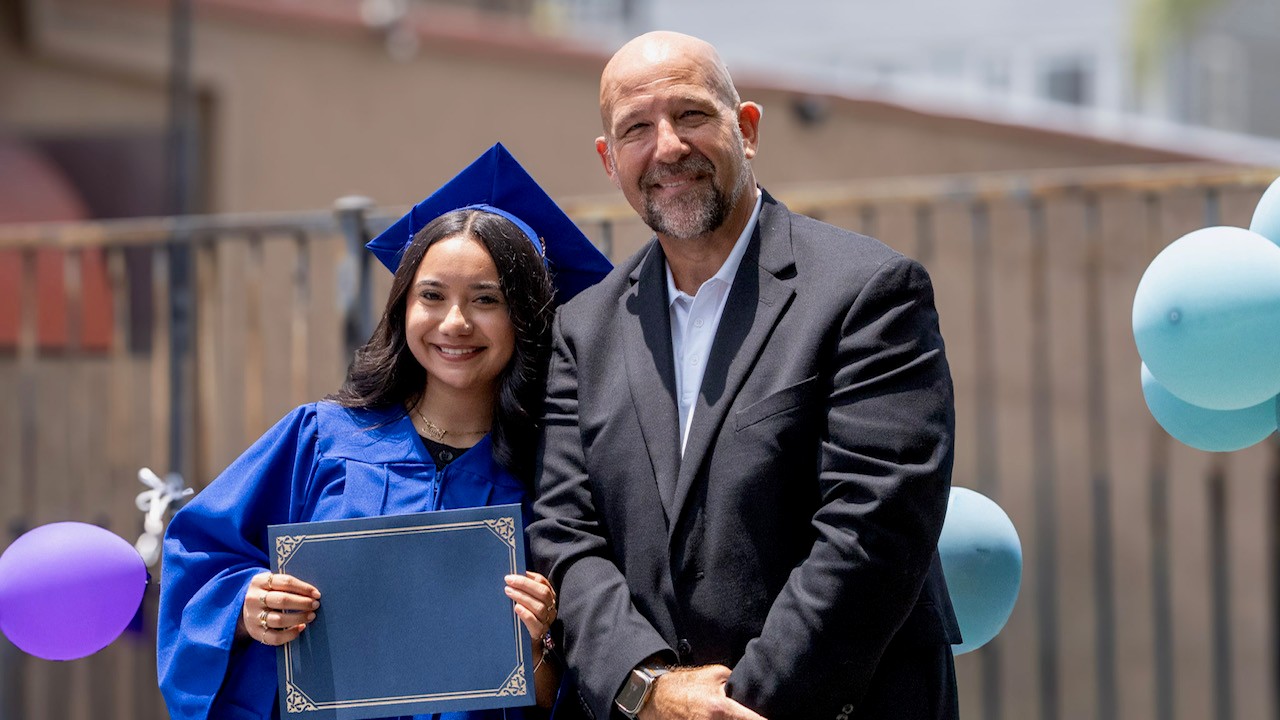 Graduate receiving diploma with Damien Weston at commencement
