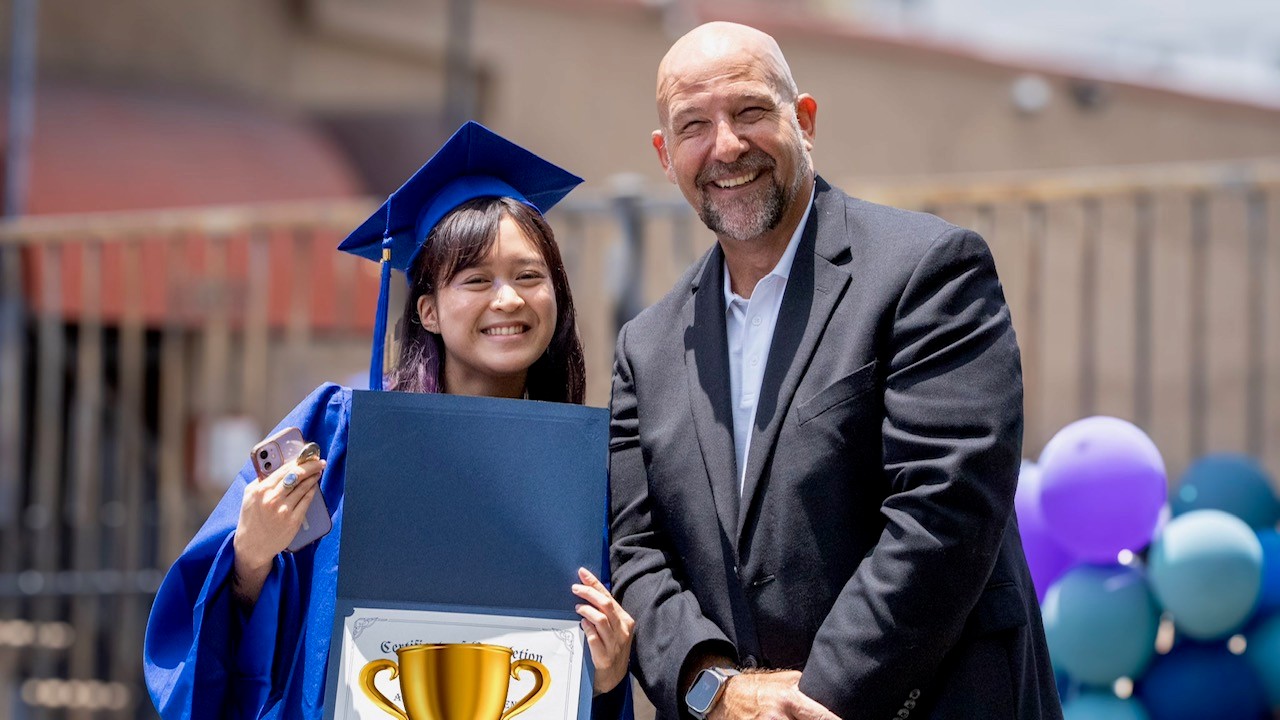 Graduate holding certificate of completion with Damien Weston