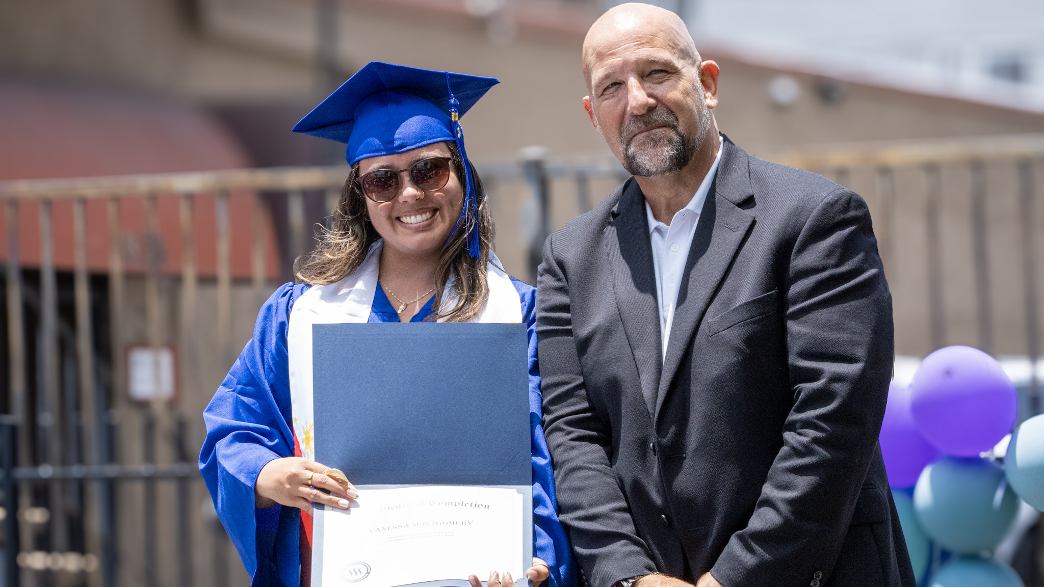 Damien Weston handing a diploma to a graduate at commencement