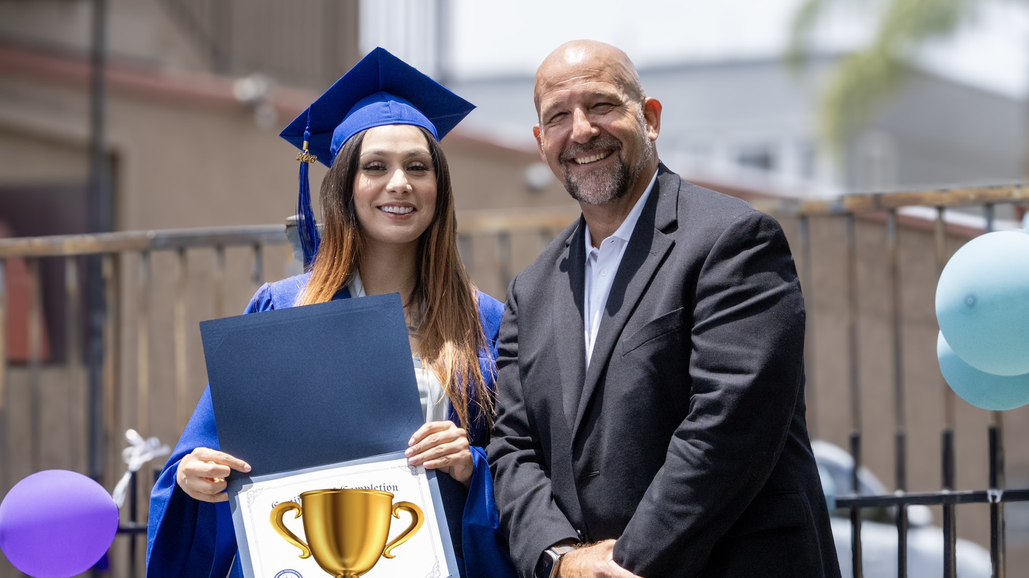 Damien Weston congratulating a graduate with diploma in hand