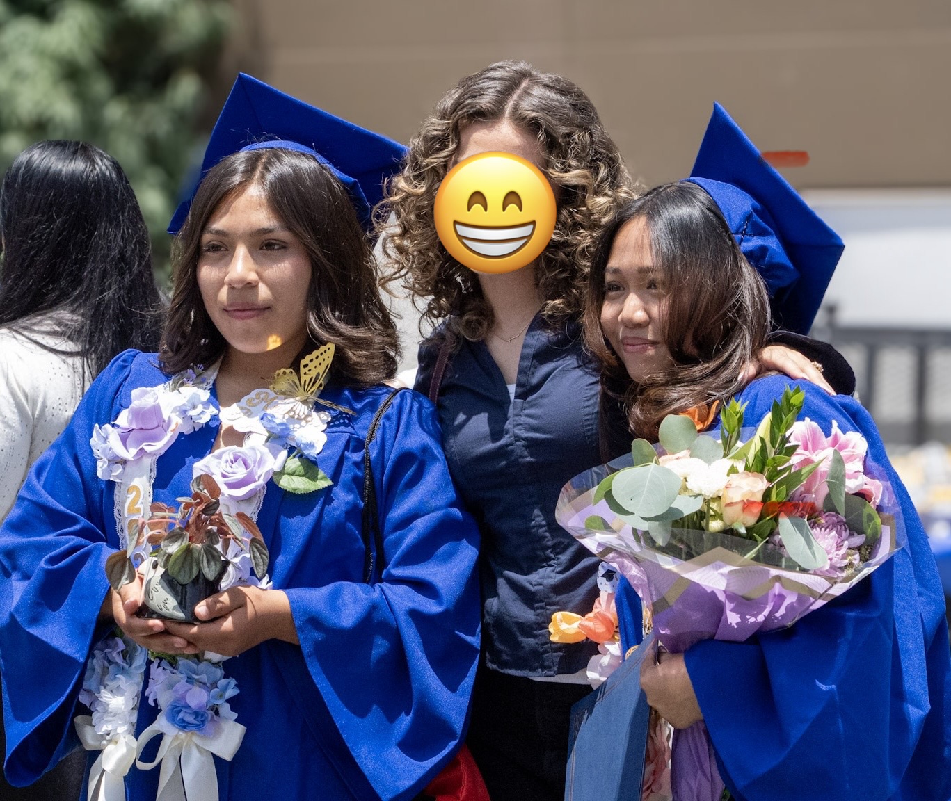 Two graduates in cap and gown with flowers after the ceremony